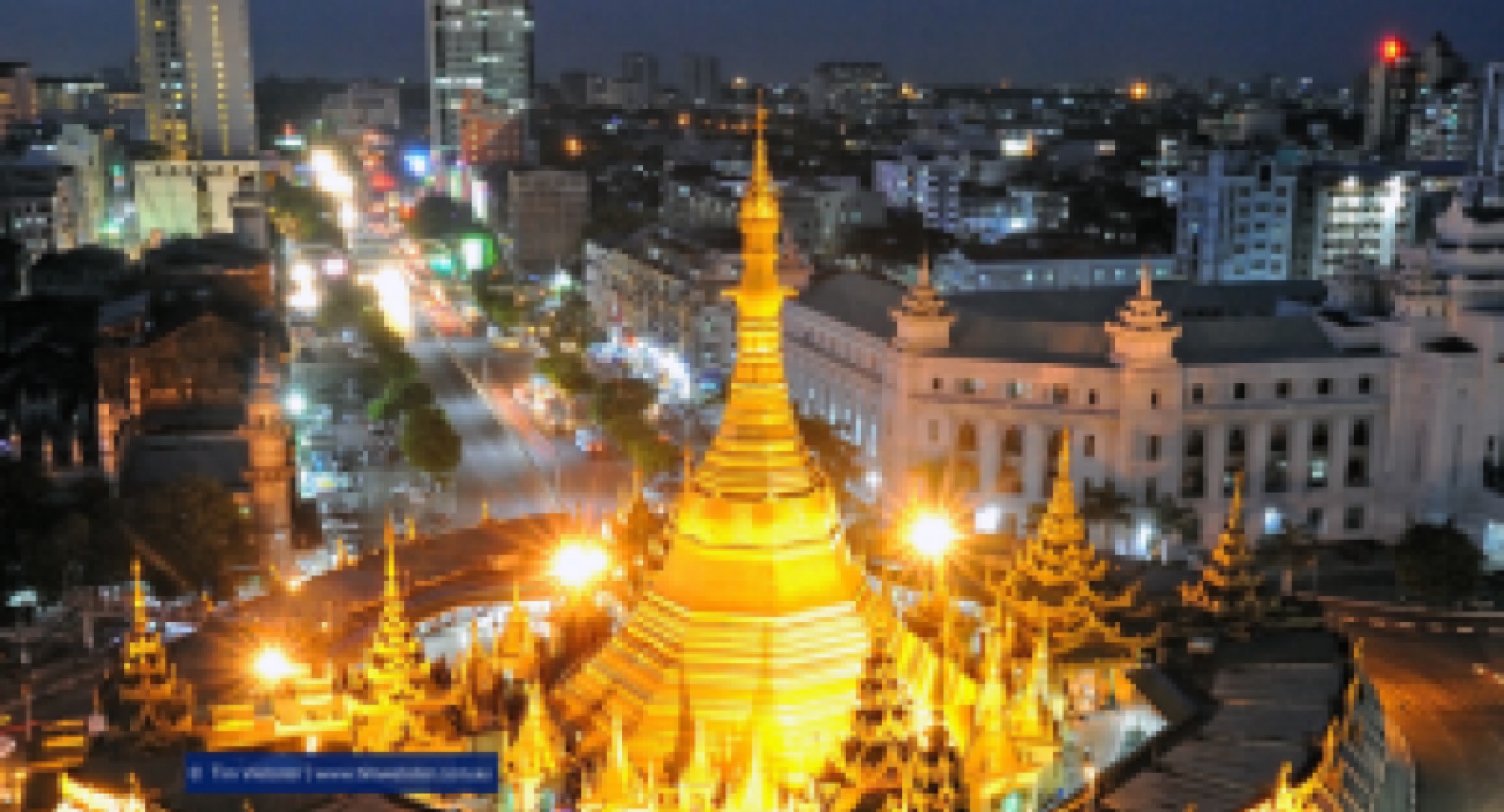 Sule Pagoda lit at night in downtown Yangon, with Yangon City Hall behind it